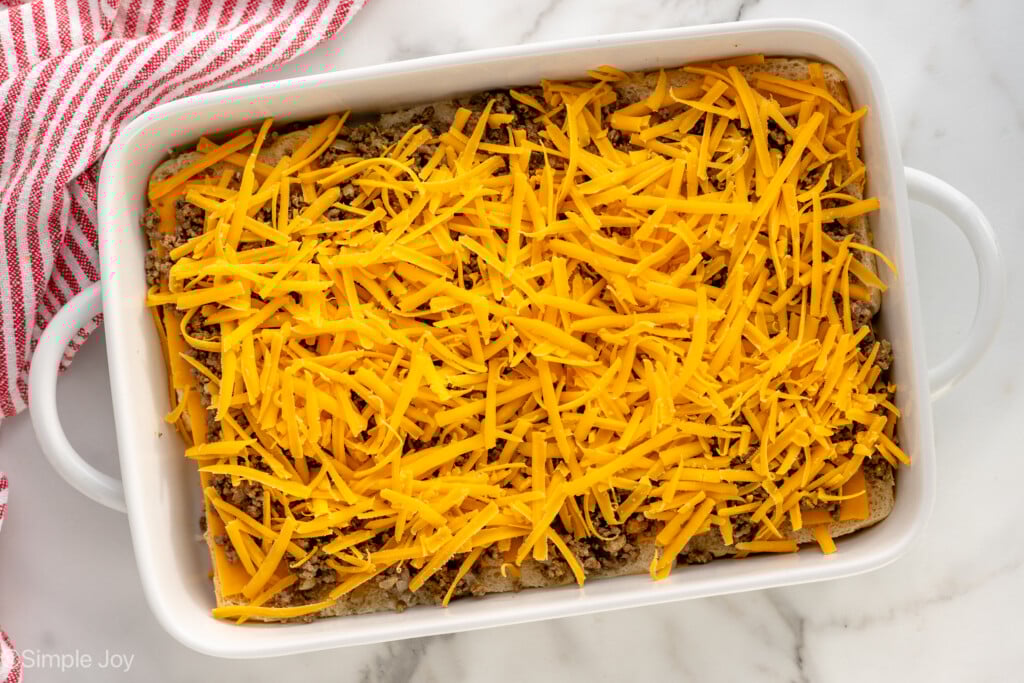 Overhead view of a baking dish with cheesy layer for Cheeseburger Sliders recipe