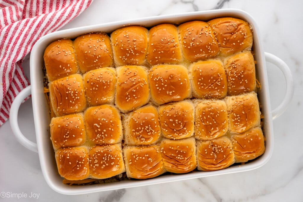 Overhead view of a baking dish of Cheeseburger Sliders garnished with sesame seeds before baking - 9