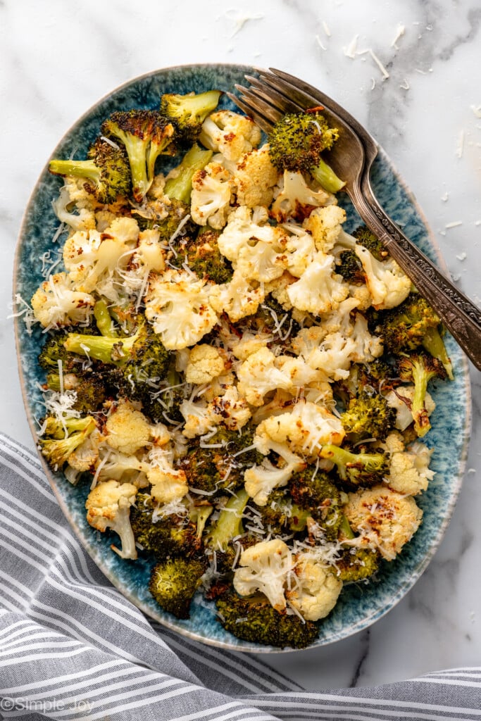 Overhead view of a platter of Roasted Broccoli and Cauliflower garnished with parmesan cheese, forks beside - 3