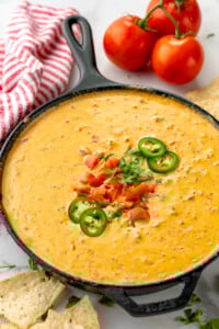 Skillet of Rotel Dip garnished with chopped tomatoes, cilantro, and sliced jalapenos. Tortilla chips and tomatoes beside. - 8