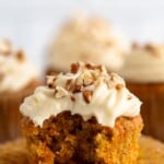 Pinterest graphic for Carrot Cake Cupcakes recipe. Text says, "Carrot Cake Cupcakes simplejoy.com." Image shows side view of a Carrot Cake Cupcake with a bite taken out, topped with cream cheese frosting and chopped walnuts.