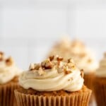 Pinterest graphic for Carrot Cake Cupcakes recipe. Text says, "Carrot Cake Cupcakes simplejoy.com." Image shows side view of Carrot Cake Cupcakes topped with cream cheese frosting and chopped walnuts.
