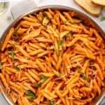 pinterest graphic of overhead of a skillet of penne alla vodka garnished with sliced basil and parmesan, says: mouth watering penne alla vodka, simplejoy.com