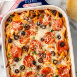 Pinterest graphic for Pizza Casserole recipe. Text says, "easy & delicious Pizza Casserole simplejoy.com." Image shows overhead view of baking dish of Pizza Casserole topped with black olives and pepperoni.