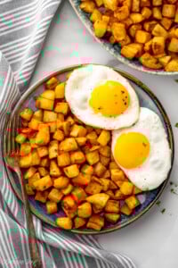 Overhead view of a plate of Air Fryer Breakfast Potatoes with eggs, fork