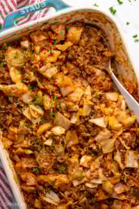 Overhead view of a baking dish of cabbage roll casserole with a spoon for serving