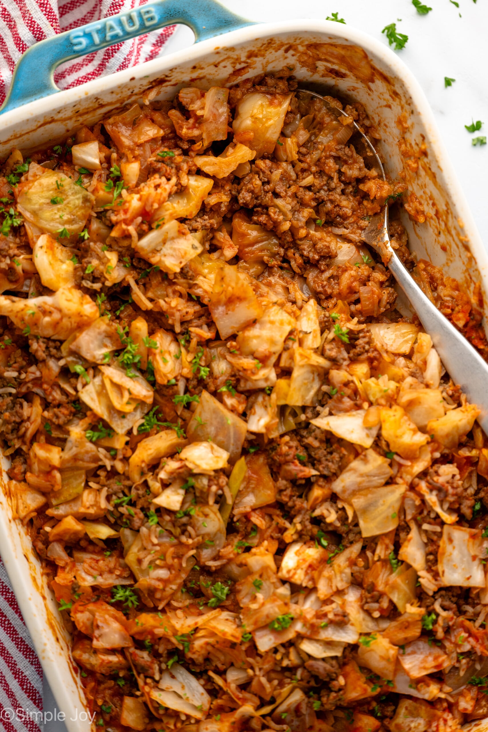 Overhead view of a baking dish of cabbage roll casserole with a spoon for serving