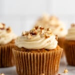 Side view of Carrot Cake Cupcakes topped with cream cheese frosting and chopped walnuts