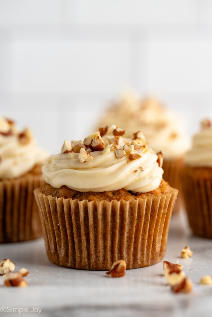 Side view of Carrot Cake Cupcakes topped with cream cheese frosting and chopped walnuts