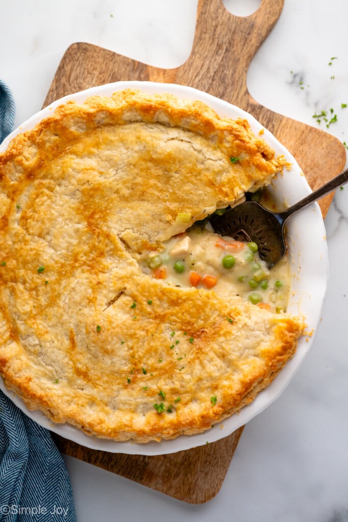 Overhead view of Chicken Pot Pie with a piece cut out and filling flowing out, serving spatula in pan.