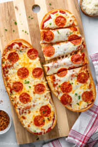Overhead view of French Bread Pizza served on wooden board with one French Bread Pizza cut into strips - 9