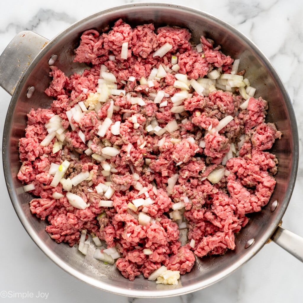 Overhead view of a skillet of ground beef and diced onion cooking for cabbage roll casserole recipe