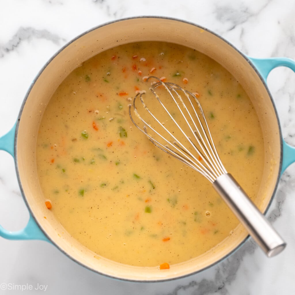 Overhead view of a pot of ingredients with a whisk for Chicken Pot Pie recipe