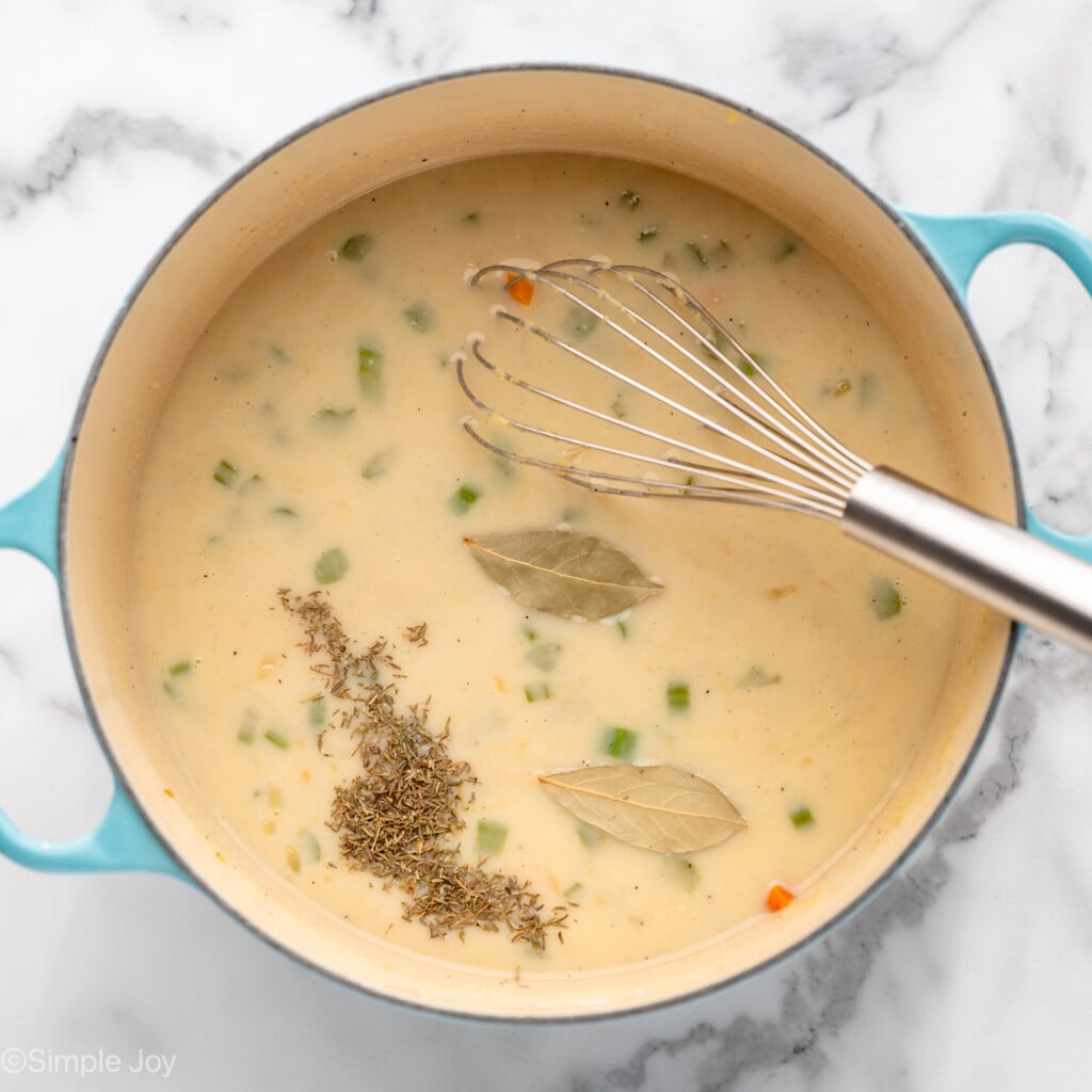 Overhead view of a pot of ingredients and seasonings with whisk for Chicken Pot Pie recipe