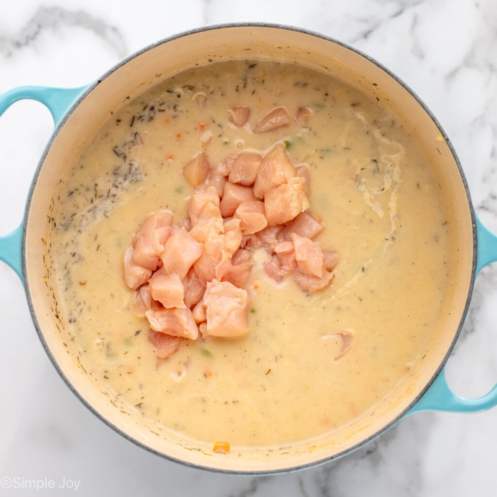 Overhead view of a pot with ingredients and cubes of raw chicken for Chicken Pot Pie recipe