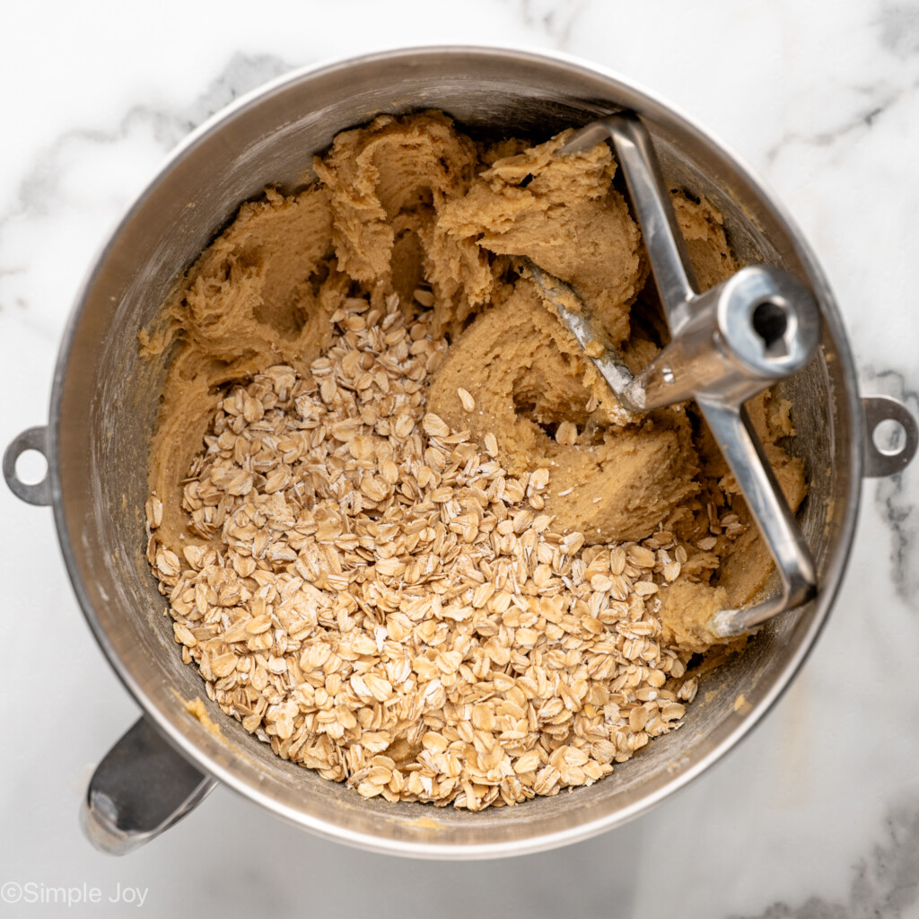 Overhead view of mixing bowl with ingredients and beater for Oatmeal Raisin Cookies recipe