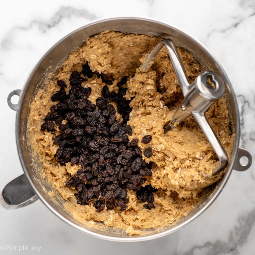 Overhead view of mixing bowl with beaters and ingredients for Oatmeal Raisin Cookies recipe