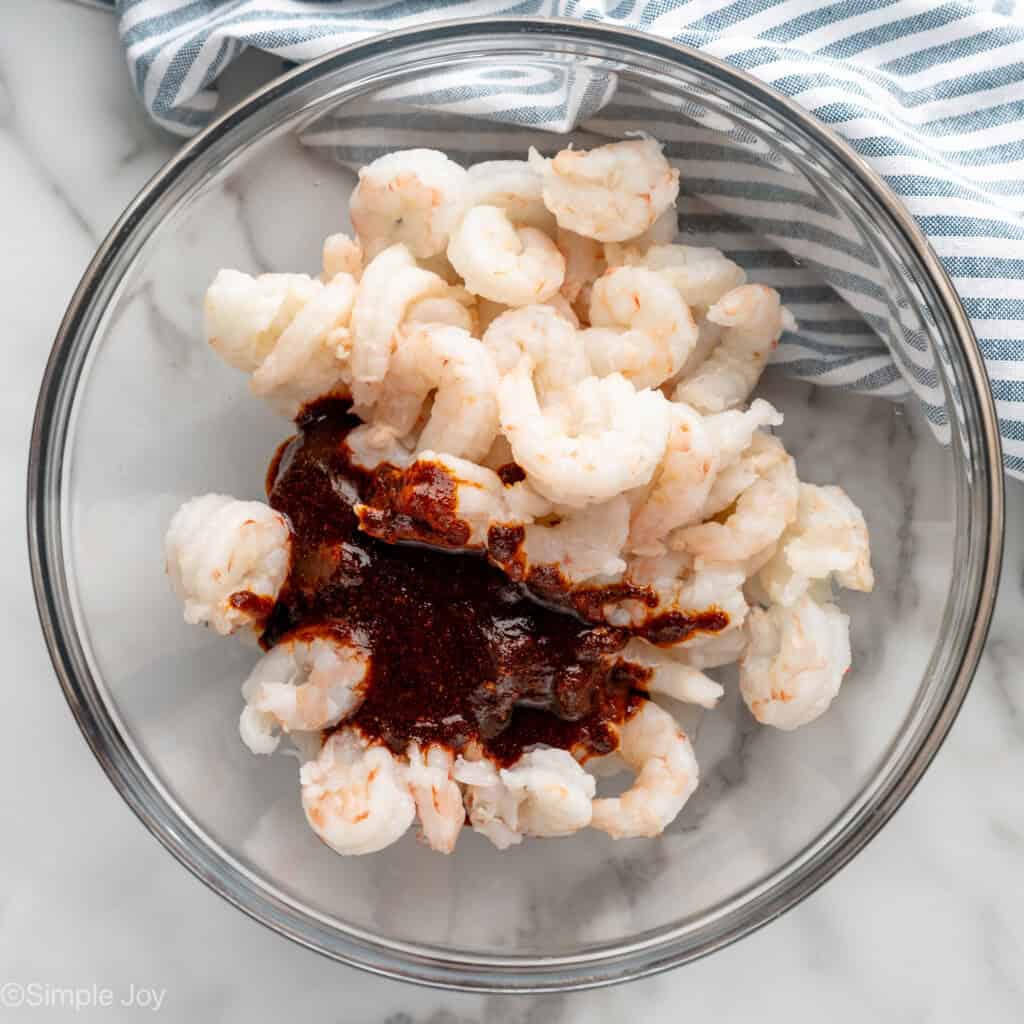 overhead of bowl of shrimp with a marinade added to the bowl