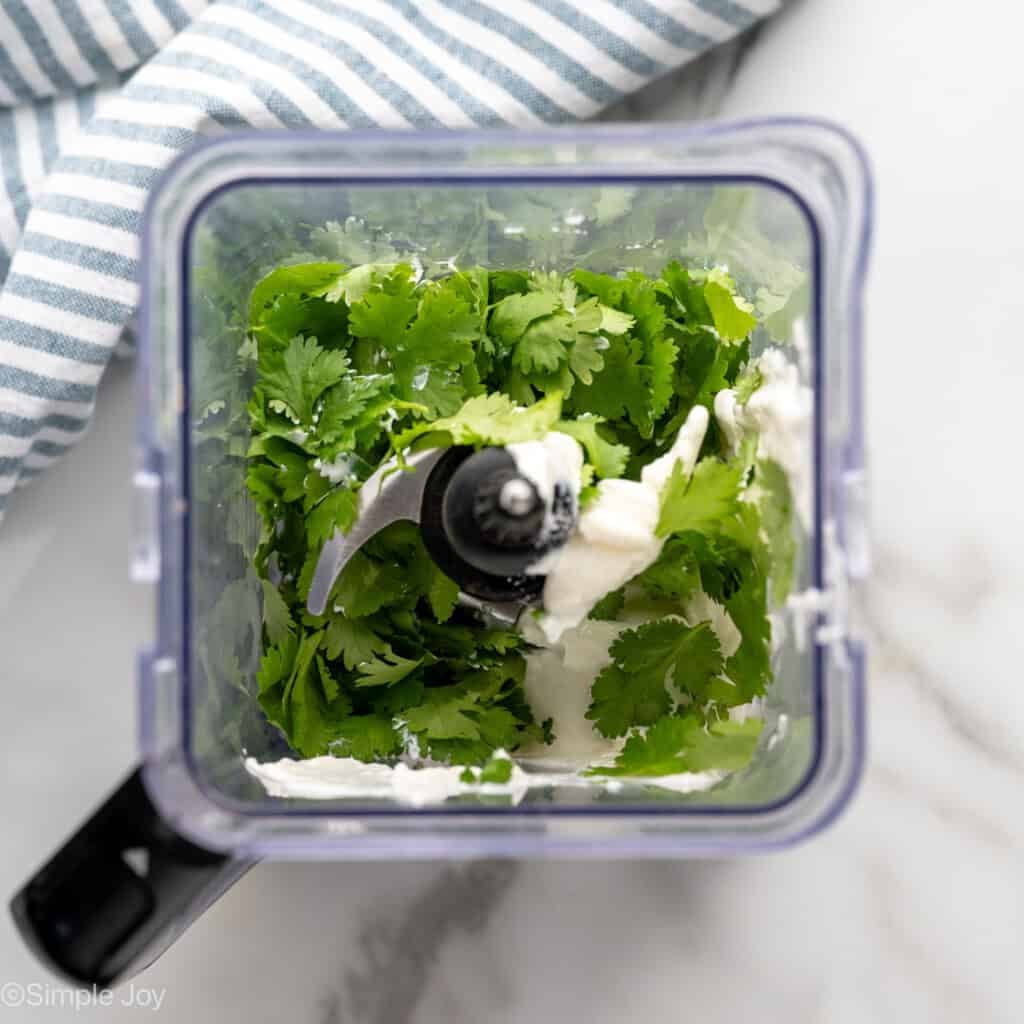 overhead of a blender full of sour cream and fresh cilantro