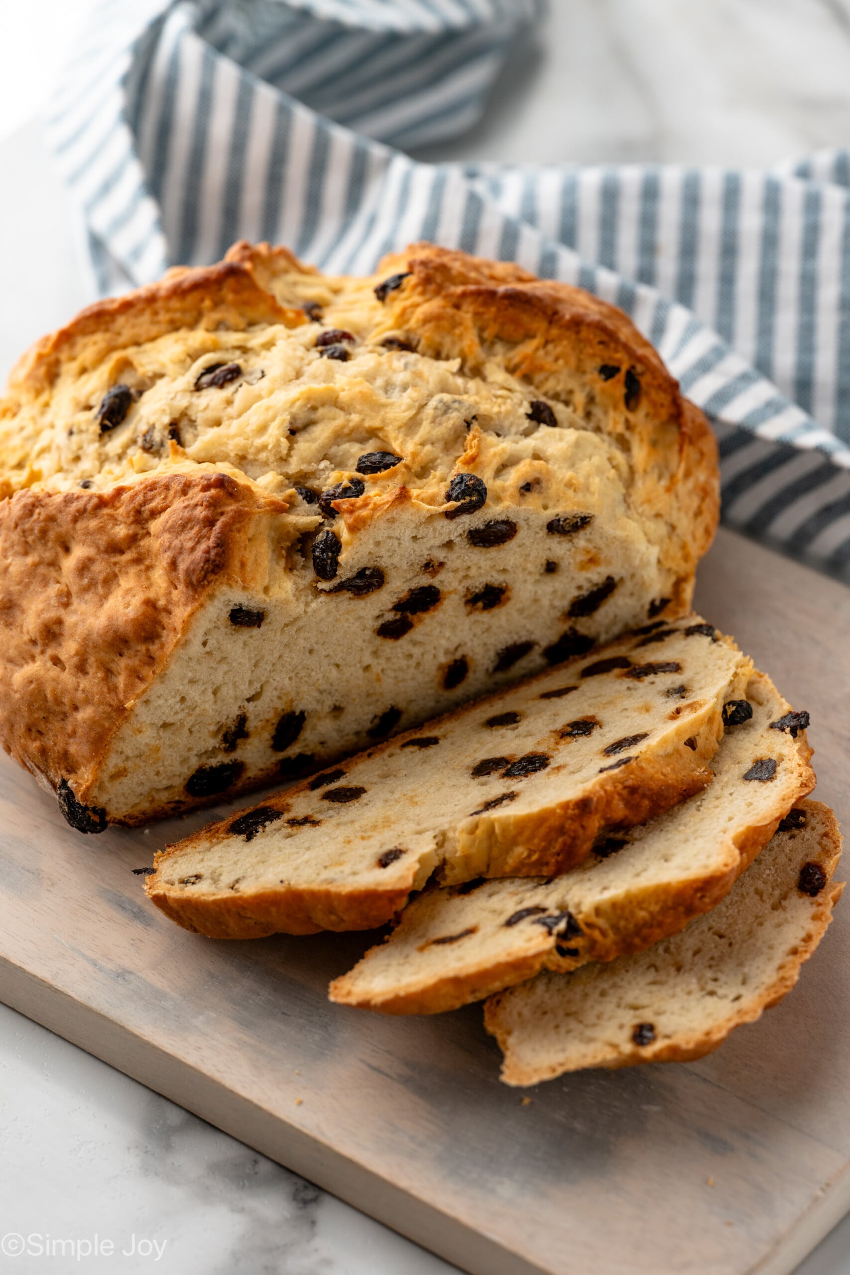 Loaf of Irish Soda Bread on wooden board partially sliced