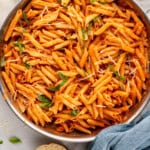 overhead of a skillet of penne alla vodka garnished with sliced basil and parmesan