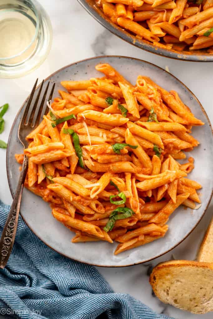 overhead of a plate of penne alla vodka recipe with parmesan and sliced basil