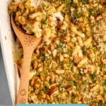 Pinterest graphic for Chicken and Stuffing Casserole recipe. Image shows overhead view of a baking dish of Chicken and Stuffing Casserole recipe with a wooden spoon. Text says, "super easy Chicken & Stuffing Casserole simplejoy.com."