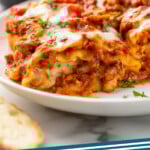 Pinterest graphic for Lasagna Roll Ups recipe. Image shows plate of Lasagna Roll Ups topped with fresh parsley. Text says, "Lasagna Roll Ups simplejoy.com."