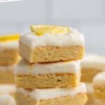 Pinterest graphic for Lemon Sugar Cookie Bars recipe. Text says, "the best lemon cookie bars simplejoy.com." Image shows a stack of Lemon Sugar Cookie Bars with lemon wedges.