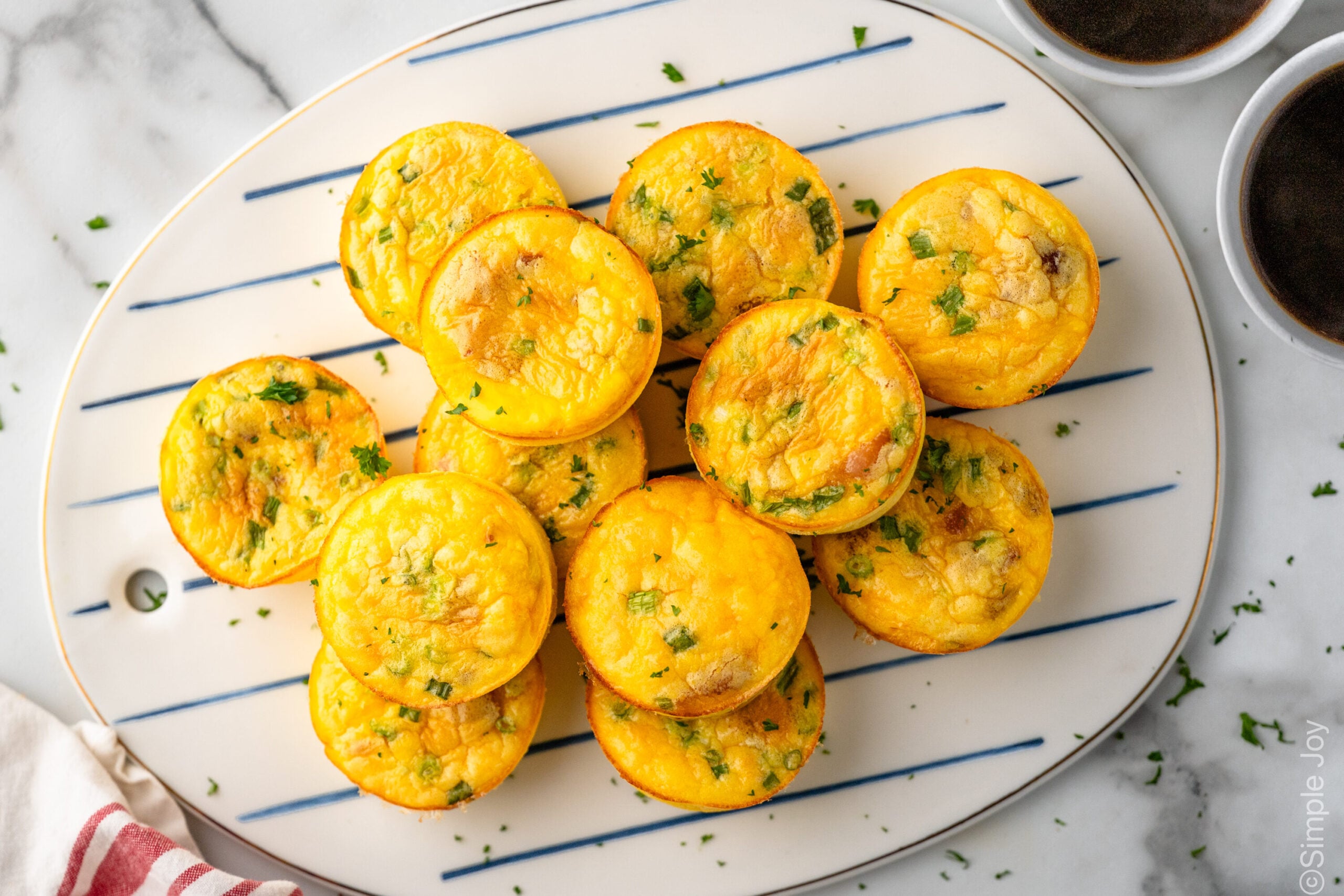 Overhead view of a platter of Cottage Cheese Egg Bites topped with herbs