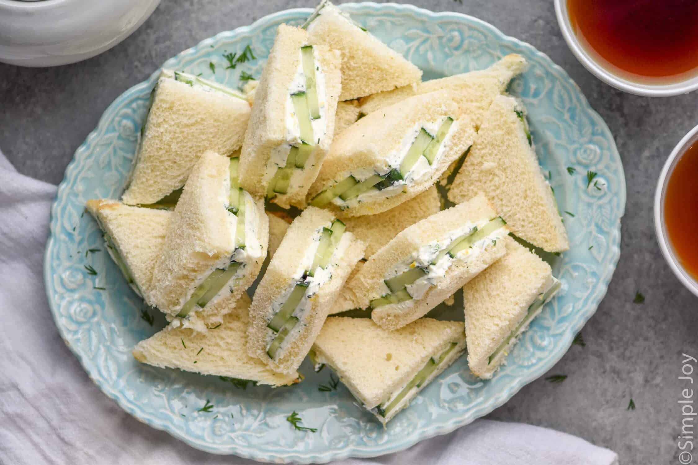 overhead of blue plate of cut cucumber sandwiches
