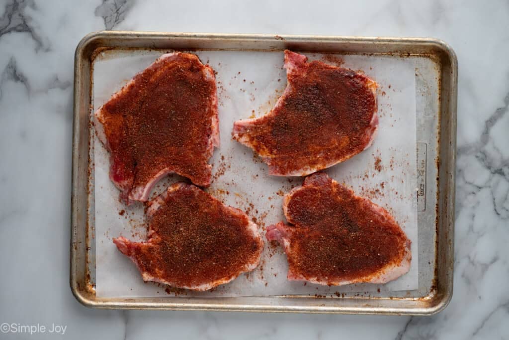 overhead of seasoned pork chops on a baking sheet to make Baked Pork Chops