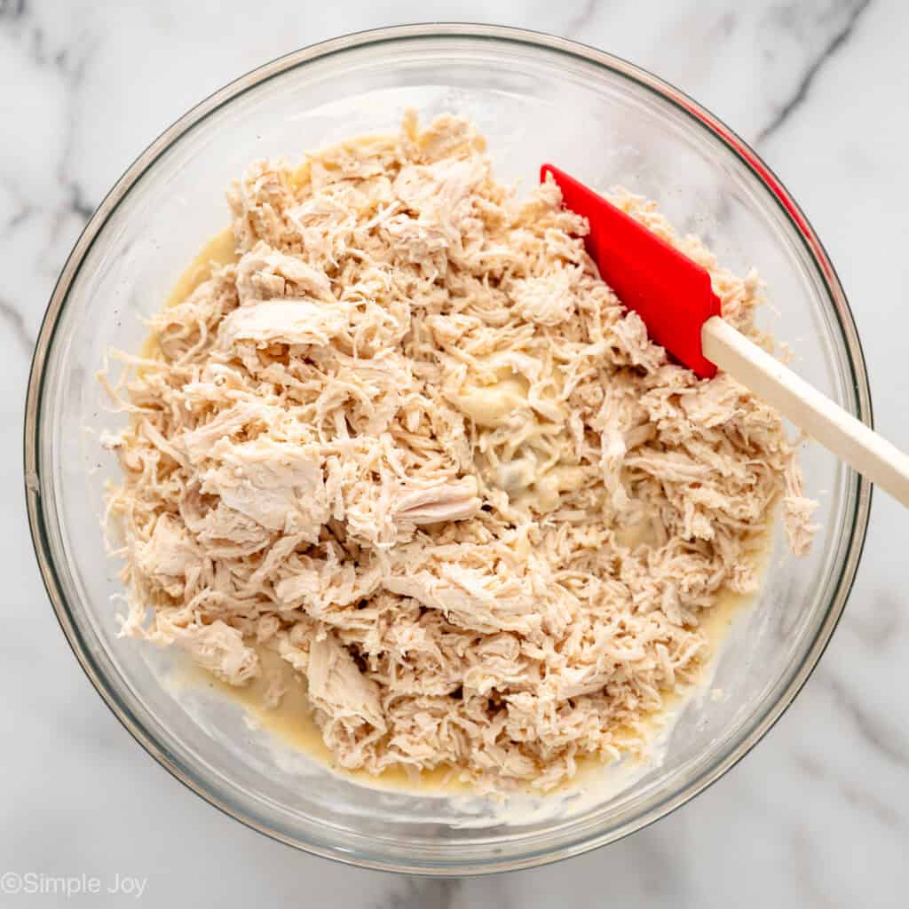 Overhead view of mixing bowl of shredded chicken and other ingredients with spatula for Chicken and Stuffing Casserole recipe