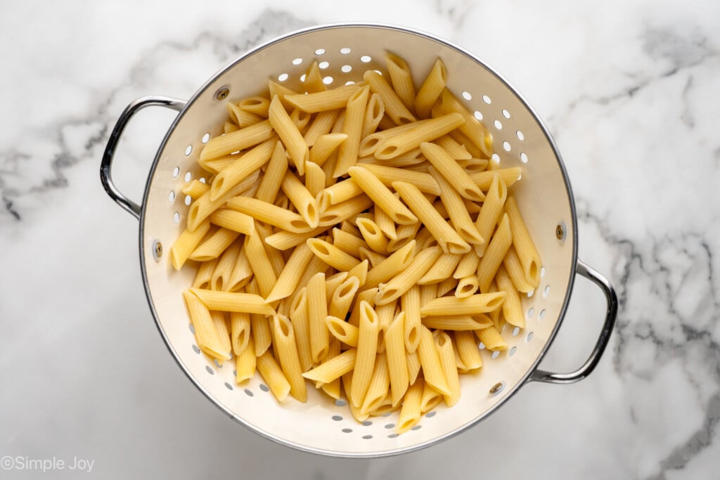 Overhead view of a colander of penne pasta for Chicken Penne Pasta recipe