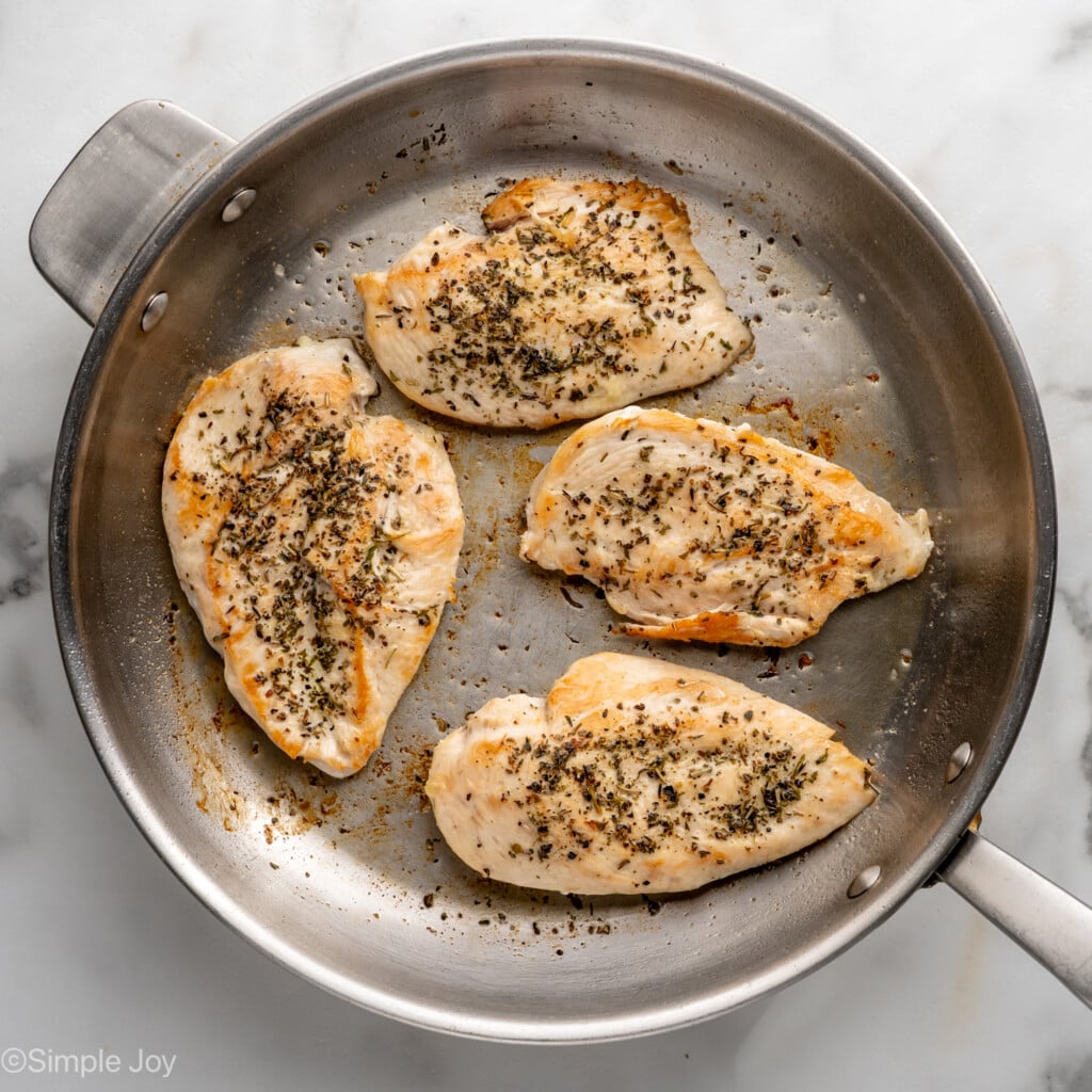 Overhead view of a skillet with chicken breasts cooking for Chicken Penne Pasta recipe