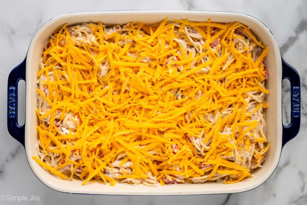 overhead of baking dish of chicken spaghetti topped with shredded cheese
