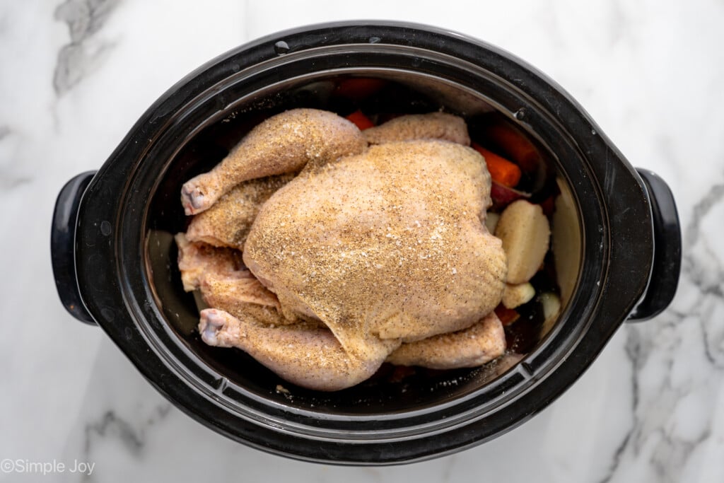 overhead of slow cooker with raw whole chicken for making Crockpot Whole Chicken