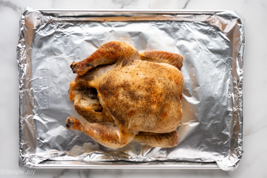 overhead of foiled-lined baking sheet with whole chicken for making Crockpot Whole Chicken