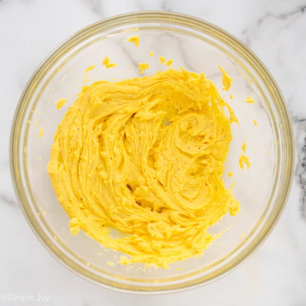 Overhead view of a mixing bowl of filling for Deviled Eggs with Bacon recipe