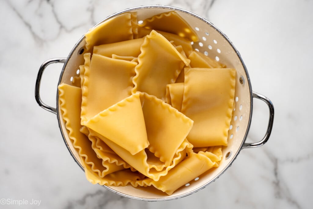 Overhead view of a colander of lasagna noodles for Lasagna Roll Ups recipe