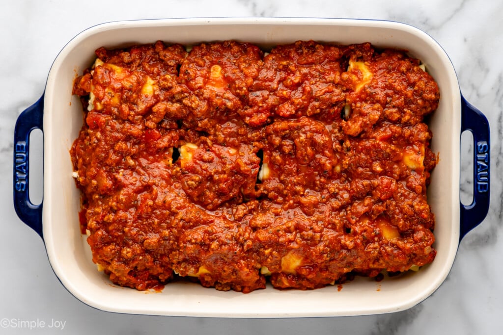 Overhead view of baking dish of Lasagna Roll Ups recipe with sauce on top, before baking