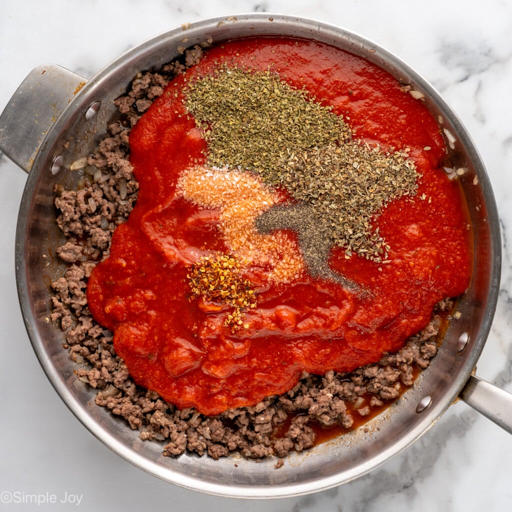 Overhead view of a skillet of ground beef with sauce and seasonings on top for Lasagna Roll Ups recipe