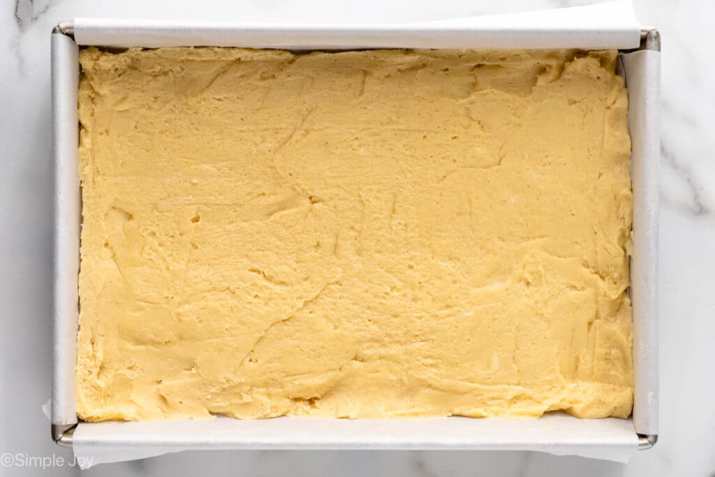 Overhead view of a baking sheet with crust for Lemon Sugar Cookie Bars recipe before baking