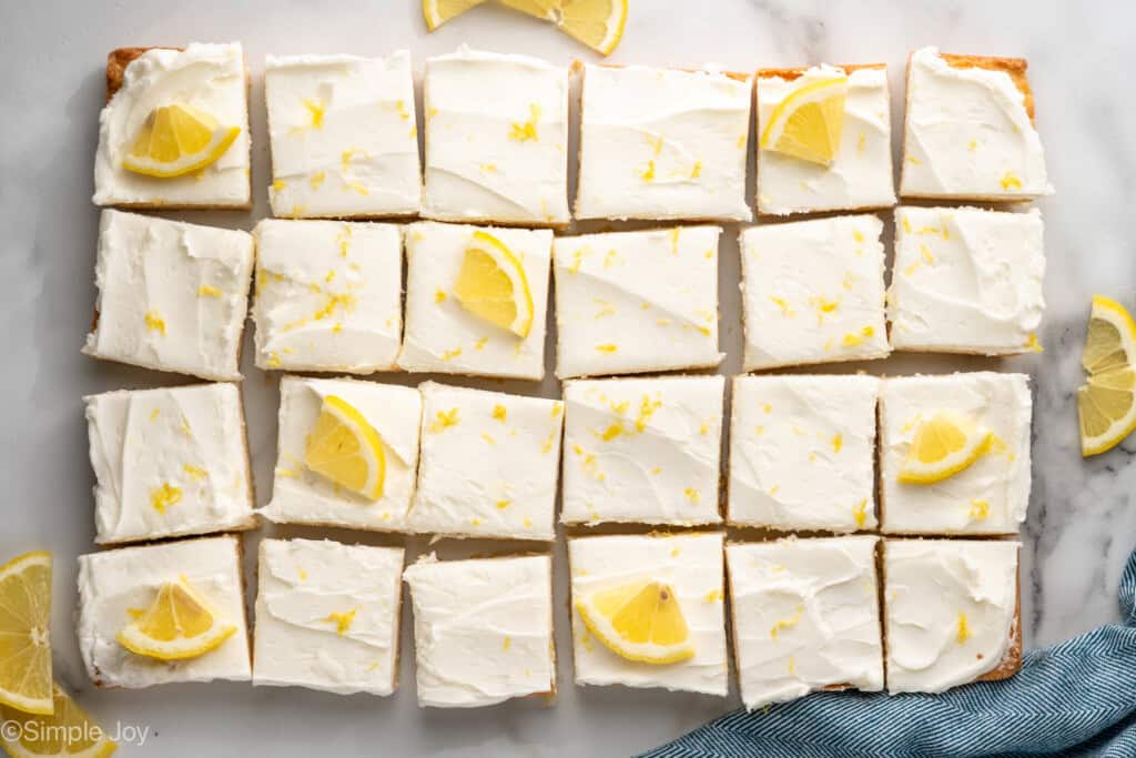 Overhead view of sliced Lemon Sugar Cookie Bars garnished with lemon zest and lemon slices