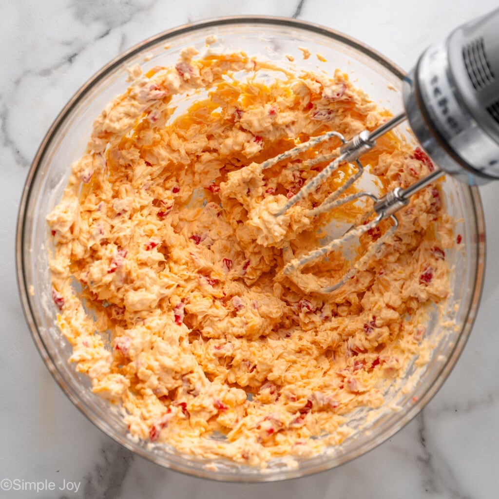 Overhead view of a mixing bowl of Pimento Cheese recipe with beaters for mixing
