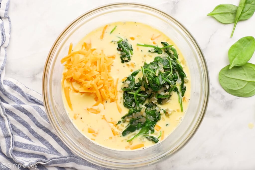 Overhead of glass bowl of spinach quiche filling ingredients