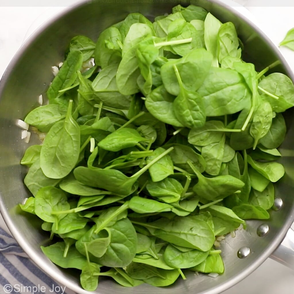 overhead of fresh spinach in a skillet to make spinach quiche