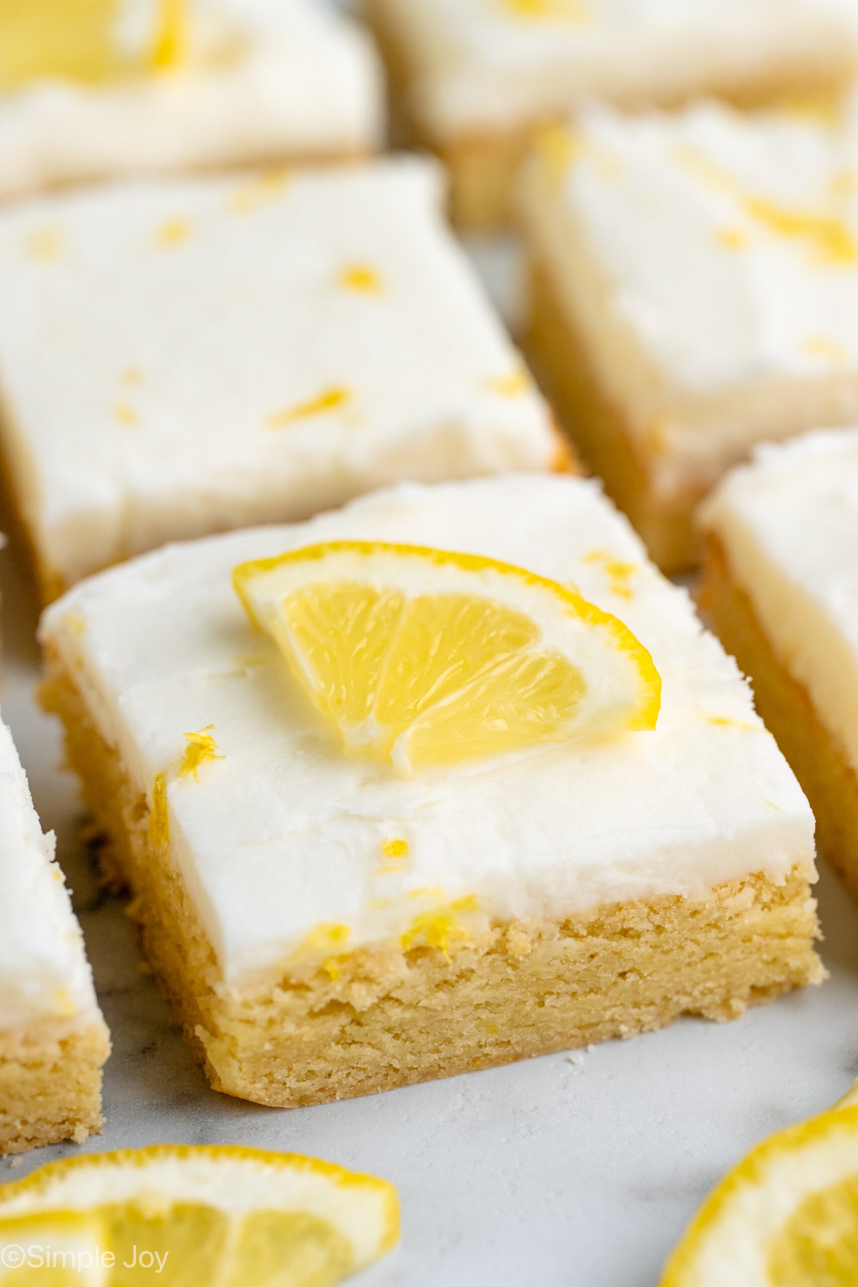 Sliced Lemon Sugar Cookie Bars garnished with lemon zest and slices of lemon.