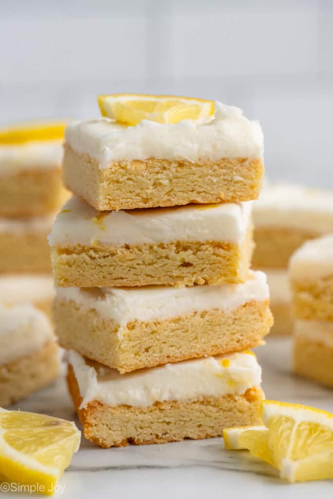 Stack of Lemon Sugar Cookie Bars with lemon wedges beside.