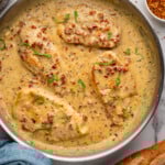Overhead of skillet of Marry Me Chicken with baguette sitting beside